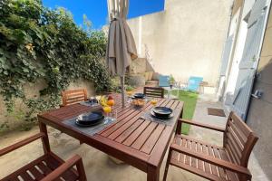 a wooden table with two chairs and an umbrella at Le Grand Bleu TerrasseClimWifiNetflix Proche Gare-Centre in Marseille