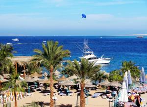 a boat in the ocean and a beach with palm trees at Bella Vista Resort Hurghada Families And Couples Only in Hurghada