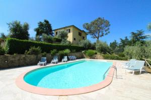 a swimming pool with chairs and a house in the background at Il Poggiolo in Monte San Savino