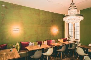 Hotel Villa Klemm - Wiesbaden City في فيسبادن: صف طاولات في مطعم بجدار أخضر