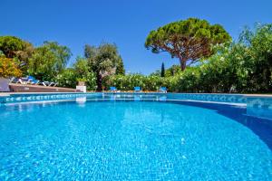 a large blue swimming pool with chairs and trees at Villa Savannah by Algarve Vacation in Almancil