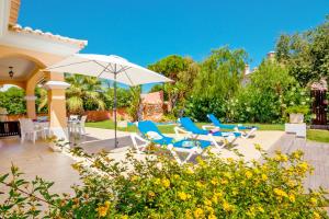a patio with blue and white chairs and an umbrella at Villa Savannah by Algarve Vacation in Almancil