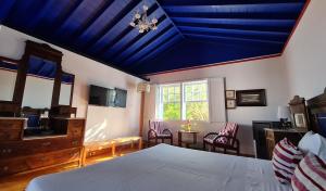 a bedroom with a blue ceiling with a bed and chairs at Quinta da Meia Eira in Horta