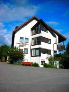 ein großes weißes Gebäude mit einer Bank davor in der Unterkunft Gasthof Siller in Spiegelberg