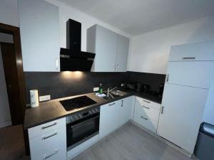 uma cozinha com armários brancos e um forno com placa de fogão em HomesNRW - 2OG / City / Messe em Bergisch Gladbach