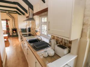 a kitchen with white cabinets and a stove top oven at Knap Cottage in Walton East