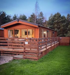uma cabana com uma cerca de madeira na relva em Hazel Oaks, Beautiful Lodge with Hot Tub - Sleeps 6 - Felmoor Park em Morpeth