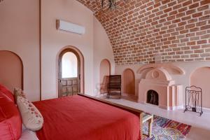 a bedroom with a red bed and a brick wall at Maya Garh Pushkar in Pushkar