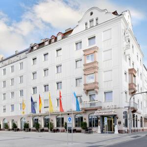 ein großes weißes Gebäude mit Flaggen davor in der Unterkunft Ringhotel Loew's Merkur in Nürnberg