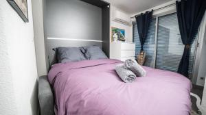a bedroom with a pink bed with towels on it at TI TAHITI STUDIO-3MIN PLAGE-TERRASSE COSY-WIFI-PARKING - TOP PROS SERVICESConciergerie La Grande Motte in La Grande-Motte