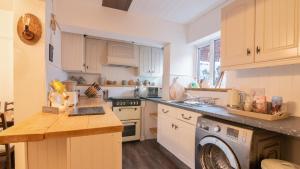 a kitchen with white cabinets and a washer at Cosy cottage near Saltburn & Whitby in Boosbeck