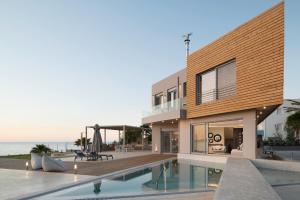 a house with a swimming pool in front of the ocean at An intimate Villa Resort- Right on the beach, by ThinkVilla in Petres