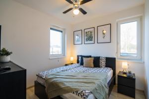 a bedroom with a bed and two windows at BlackWood '66 Apartman in Siófok