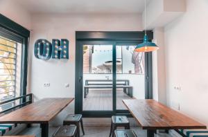 a room with a table, chairs, and a clock on the wall at Oasis Backpackers' Hostel Sevilla & Coworking in Seville