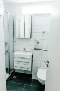 a white bathroom with a sink and a toilet at Haus Vier Jahreszeiten am See Apartment am Kranichsee in Hahnenklee-Bockswiese +23 photos