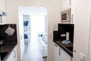 cocina con microondas y sala de estar. en Haus Vier Jahreszeiten am See Apartment am Kranichsee, en Hahnenklee-Bockswiese