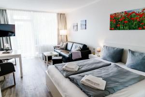 - une chambre avec un lit et un salon avec un canapé dans l'établissement Haus Vier Jahreszeiten am See Apartment am Kranichsee, à Hahnenklee