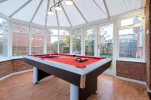 a pool table in a room with windows at WILLIAM HOMES - COOMBE ABBEY, Free Parking, King BED, NETFLIX & Pool Table in Coventry