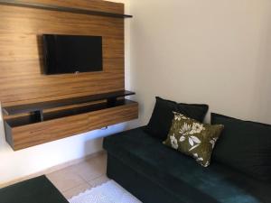 a living room with a black couch and a flat screen tv at Jo´s Apartment in Porto Seguro