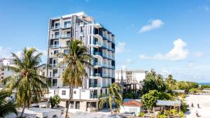 馬富施的住宿－Triton Prestige Seaview and Spa，海滩前有棕榈树的高大的白色建筑