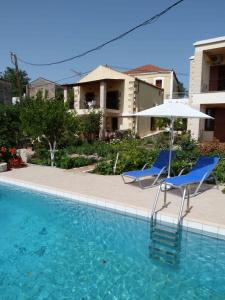 two chairs and an umbrella next to a swimming pool at The Garden Villas in Maleme