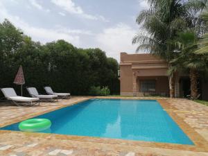a pool with chairs and a frisbee in front of a house at Dar LALA NEJMA in Marrakesh +22 photos