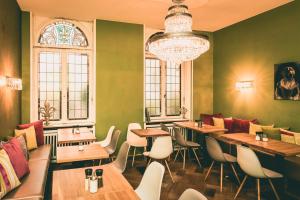 ein Restaurant mit Tischen und Stühlen und einem Kronleuchter in der Unterkunft Villa Klemm Boutique Hotel - Wiesbaden City in Wiesbaden