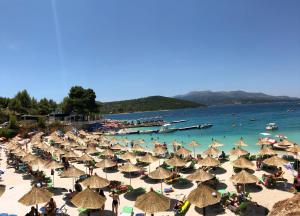 ein Strand mit vielen Sonnenschirmen und Menschen im Wasser in der Unterkunft Bora Bora Hotel Ksamil in Ksamil