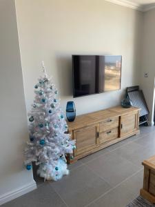 un albero di Natale bianco in un soggiorno con TV di Flat 14 Block 6 Bellamare a Port Elizabeth