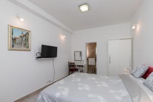a white bedroom with a bed and a tv at Apartment & Rooms Primi with FREE PARKING in Dubrovnik