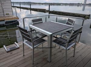 a table and two chairs on a dock near the water at Ostsee Hausboot Schleswig Ostseeblick 1 in Schleswig