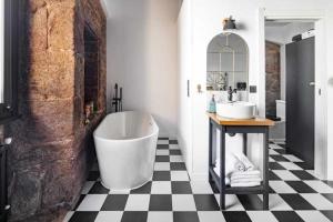 a bathroom with a large white tub and a checkered floor at La Suite Años 20. Bañera, chimenea y terraza. in Corcubión +13 photos