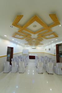 a room with white chairs and tables and a ceiling at Hotel Palmyra Grand Inn in Tirunelveli