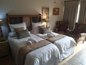 Kromdraai Guest Rooms في Kromdraai: غرفة نوم بسريرين يوجد عليها حيوانات محشوة