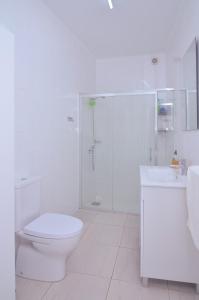 a white bathroom with a toilet and a shower at Sunrise House- 4 bedroom house with amazing sunrise over the sea 10 guests in Vila Franca do Campo
