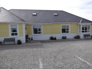 a yellow house with a bench in front of it at Ashley Lodge Bed & Breakfast in Rosslare