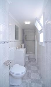 a white bathroom with a toilet and a sink at Sunrise House- 4 bedroom house with amazing sunrise over the sea 8 guests in Vila Franca do Campo