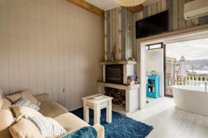 uma sala de estar com um sofá, uma televisão e uma banheira em Mar no Camiño Terraza bañera con vista al mar em Brens