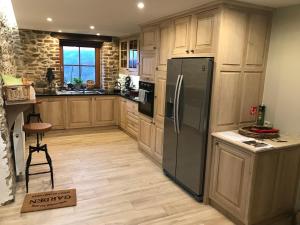 uma cozinha com armários de madeira e um frigorífico de aço inoxidável em La Source de Chession em Stoumont