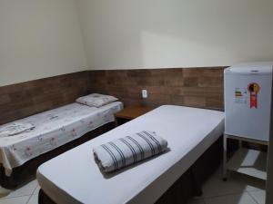 a room with two beds and a refrigerator at Hotel Porto Real in Pôrto Real