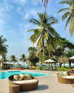 a swimming pool with two lounge chairs and palm trees at Kololi Beach Resort in Kololi