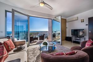 a living room with a couch and a tv and glass windows at Fuseta Apartments - Bela Vista & Vista Mar - Penthouses in Fuzeta
