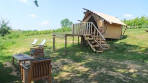 eine Hütte mit einer Terrasse und Stühlen auf einem Feld in der Unterkunft LOVE HORIZON in Monprimblanc