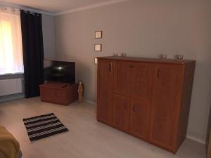 a living room with a wooden cabinet and a tv at Apartament Mariacka Two in Bydgoszcz