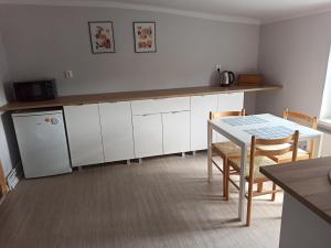 a kitchen with white cabinets and a table and a table and chairs at Apartament Mariacka Two in Bydgoszcz