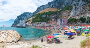 een groep mensen op een strand met parasols bij Modern Studio Apartment at The Hub in Gibraltar