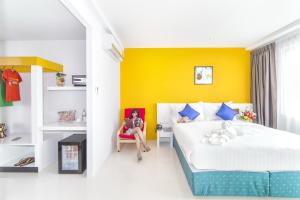 a bedroom with a bed and a yellow wall at The Frutta Boutique in Patong Beach