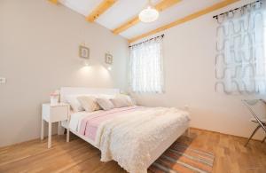 a white bedroom with a bed and a window at Aldo Apartments Center in Zadar