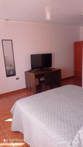 um quarto com uma cama e uma secretária com uma televisão em Alto Noa San Pedro de Atacama em San Pedro de Atacama