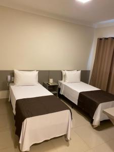 Habitación de hotel con 2 camas y mesa en VILLA NOMAD HOTEL, en Uberaba